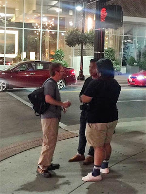 Brad St. Clair practicing street evangelism by sharing the Gospel with two men in a downtown public square.
