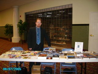 Brad St. Clair at a table filled with Gospel tracts and evangelism resources at Tri Lakes Church in Branson, Missouri.